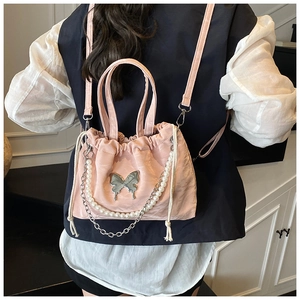 Detailed view of pink drawstring nylon bag with silver butterfly and pearl chain