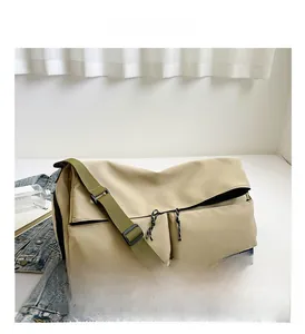 Close-up of khaki nylon gym bag with double front zippers and wide green shoulder strap