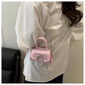 Détail du mini sac rose avec nœud en strass étincelant et bandoulière en chaîne