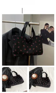 Detailed view of a black corduroy tote bag with vintage red strawberry prints