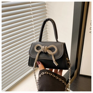 Vue détaillée du mini sac bandoulière noir avec un nœud en strass brillant et chaîne