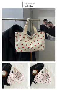 Detailed views of white corduroy tote bag featuring red strawberry patterns and top handles