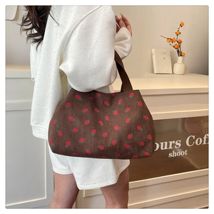 Detailed close-up of brown corduroy tote bag with strawberry print worn by a model