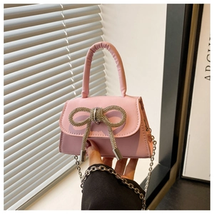 Vue détaillée d'un mini sac rose avec un nœud en strass brillant et une bandoulière argentée