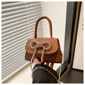 Vue détaillée du mini sac marron avec un nœud en strass brillant et une bandoulière chaîne