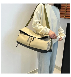 Detail of waterproof nylon gym bag featuring contrast beige panels and green shoulder strap