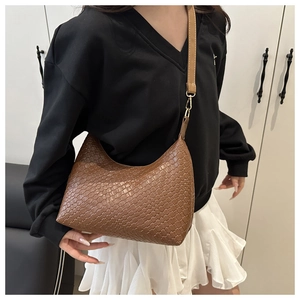 Close-up of a dark brown woven hobo bag with adjustable strap on a minimalist model outfit