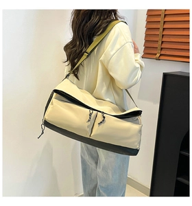 Detailed side view of off-white nylon gym bag with black base and olive green strap