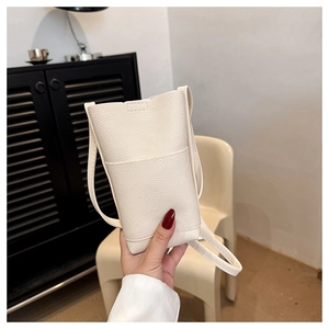 Gros plan sur le sac seau minimaliste beige à motif litchi avec poche frontale