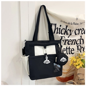 Detail of canvas tote bag with contrast pocket and cloud charm on a white background