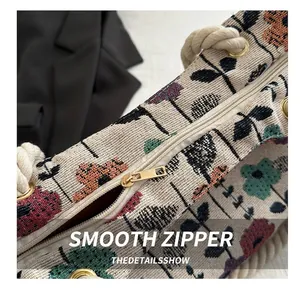 Detail showing the smooth golden metal zipper and floral canvas texture of the tote bag