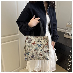Dettaglio ravvicinato della borsa tote in jacquard beige con motivi di farfalle colorate