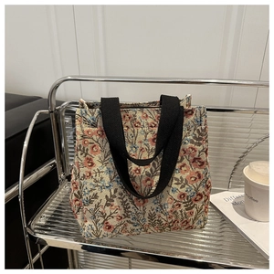 Detail of floral woven canvas tote bag featuring durable black handles on a modern shelf