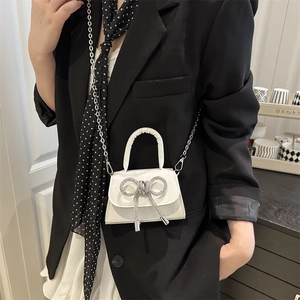 Mini sac bandoulière blanc avec nœud en strass et chaîne argentée sur veste noire