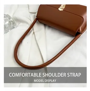 Macro shot of comfortable thickened shoulder strap and gold clasp on brown leather bag