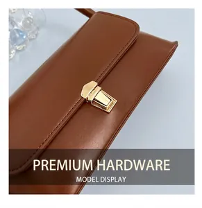 Close-up of golden metal lock detail on brown leather baguette bag for women