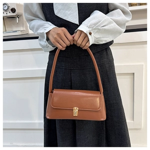 Brown leather baguette bag featuring a vintage gold metal buckle and sleek shoulder strap