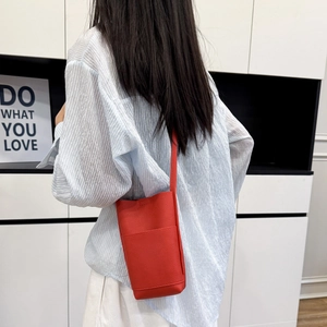 Petit sac bandoulière rouge pour téléphone portable en cuir grainé porté par un modèle