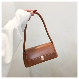Detail view of brown matte faux leather shoulder bag featuring a gold metal snap closure