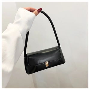 Detail of minimalist black PU leather baguette bag with elegant golden hardware lock