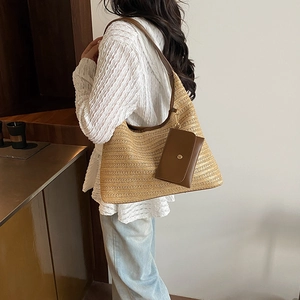 Chic beige straw woven tote bag with brown leather straps shown on a model