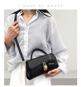 Detail of black leather crossbody bag featuring gold metal clasp and fashion charm