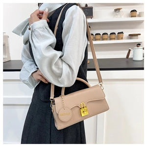 Detail of light beige PU leather crossbody bag with gold lock and fashion pendant charm