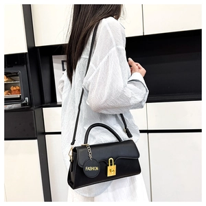 Detail of a black retro leather crossbody bag with a gold lock and fashion pendant