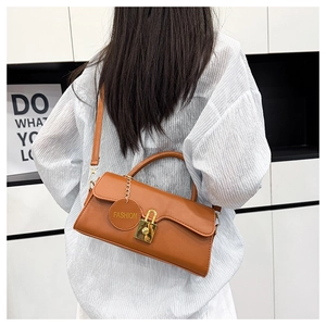 Brown retro shoulder bag with gold clasp and fashion tag on a white striped shirt