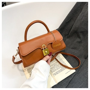 Detail of caramel PU leather bag with gold padlock closure and Fashion brand tag