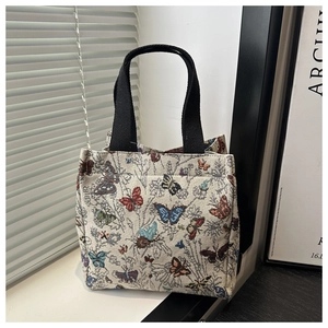 Detail of a white fabric tote bag featuring colorful embroidered butterfly patterns