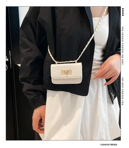 Detail of white quilted mini bag with gold chain strap and elegant twist lock closure