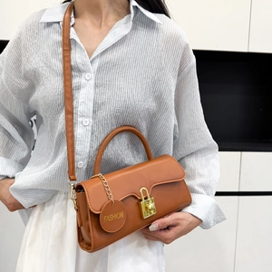 Sac bandoulière rétro en cuir marron avec boucle dorée et pendentif sur un mannequin