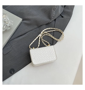 Detail of white woven leather mini flap bag with gold chain strap on a blazer