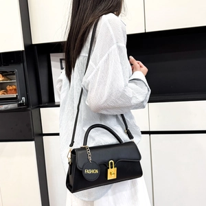 Sac bandoulière rétro en cuir noir avec fermoir doré porté par un mannequin féminin