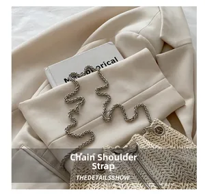 Detailed view of straw woven bag texture with silver chain strap on cream blazer