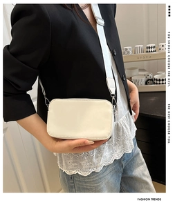 Detail of a white lychee pattern crossbody bag with wide strap worn by a model