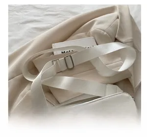 Detail of a white leather crossbody bag with wide nylon strap and black edge painting