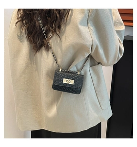 Detailed view of mini black crossbody bag with crocodile texture and gold chain strap
