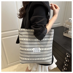 Détail du sac cabas à rayures noires et blanches montrant le tissu et l'étiquette