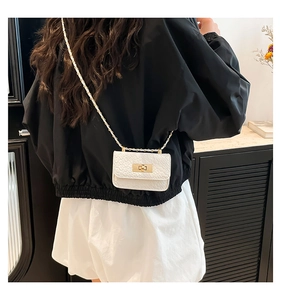 Detailed view of white mini crossbody bag with crocodile texture and gold chain strap