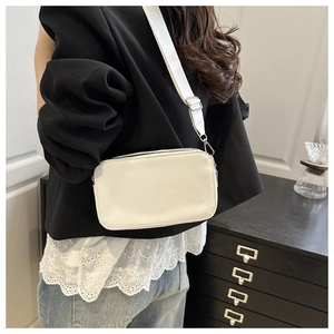 Chic off-white small square crossbody bag with a wide adjustable strap on a model