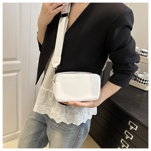Close-up of white lychee texture crossbody bag with wide fabric strap and silver hardware