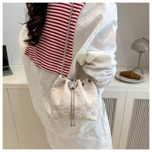 Detail of cream woven bucket bag with silver butterfly buckle and pearl tassels