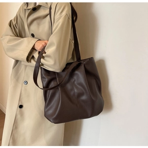 Detailed macro view showing the deep brown lychee texture leather of the tote bag