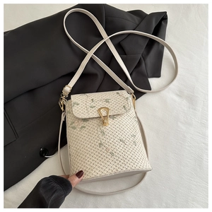 Détails de broderie et fermoir doré sur un petit sac bandoulière en paille