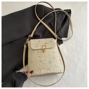 Détail d'un sac carré en paille avec broderie florale et fermoir métallique en U doré