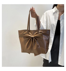 Detail of coffee brown tote bag featuring a large decorative bow and soft faux leather