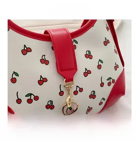 Close-up of cherry print handbag showing white leather texture and red trim details