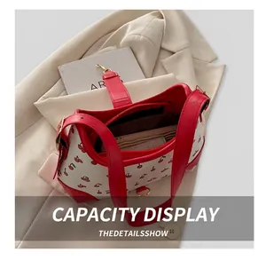 Detail showing high-capacity interior of white leather shoulder bag with cherry prints